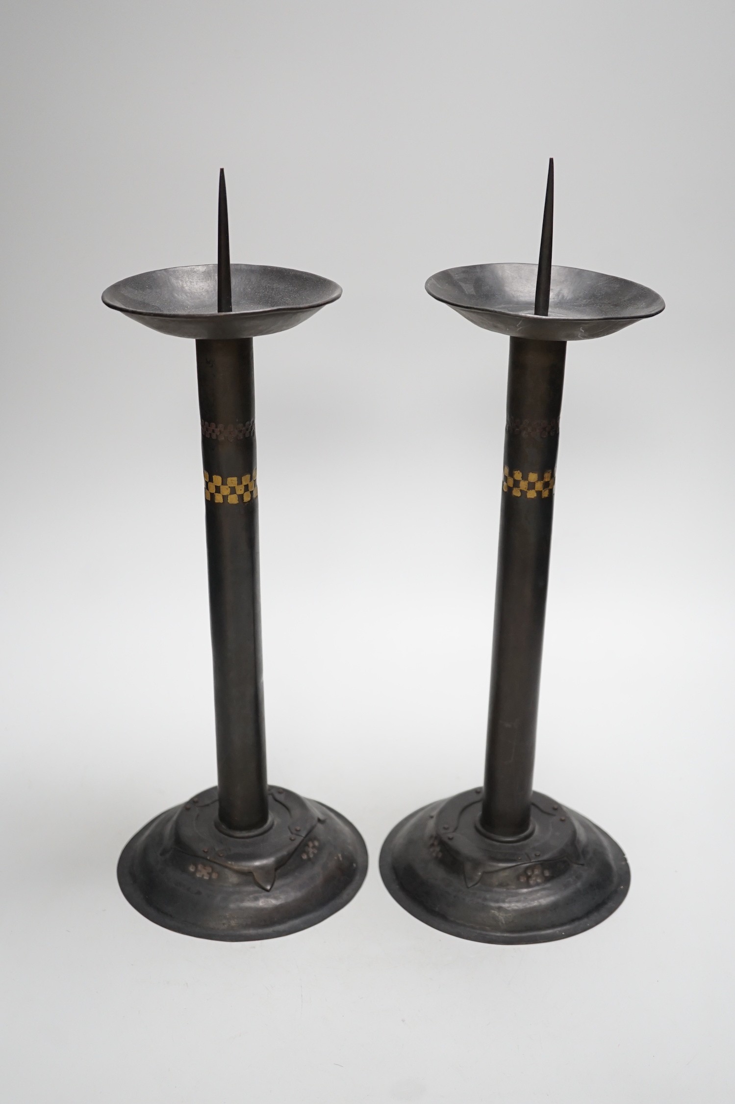 Attributed to Glasgow School of Art - a pair of Arts and Crafts pricket candlesticks. 40cm tall